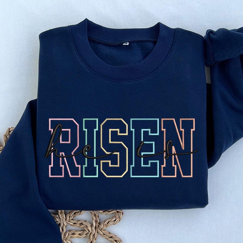 May include: Navy blue sweatshirt with the text "He is Risen" in rainbow colors.