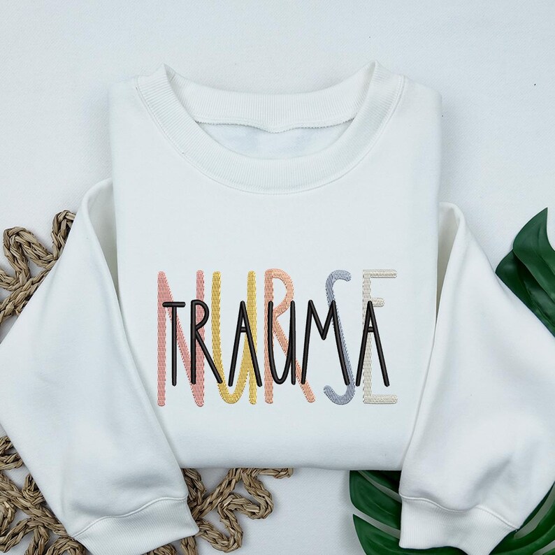 May include: White sweatshirt with the text "NURSE TRAUMA" embroidered in rainbow colors.