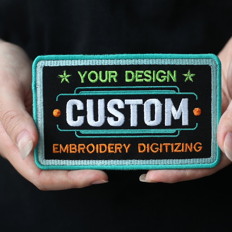 May include: A teal and black embroidered patch with white text that reads "YOUR DESIGN * CUSTOM * EMBROIDERY DIGITIZING".