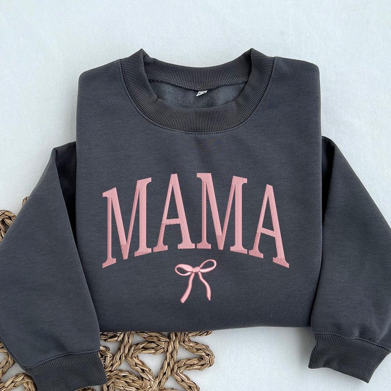 May include: A dark gray sweatshirt with the word "MAMA" in pink lettering and a pink bow underneath.