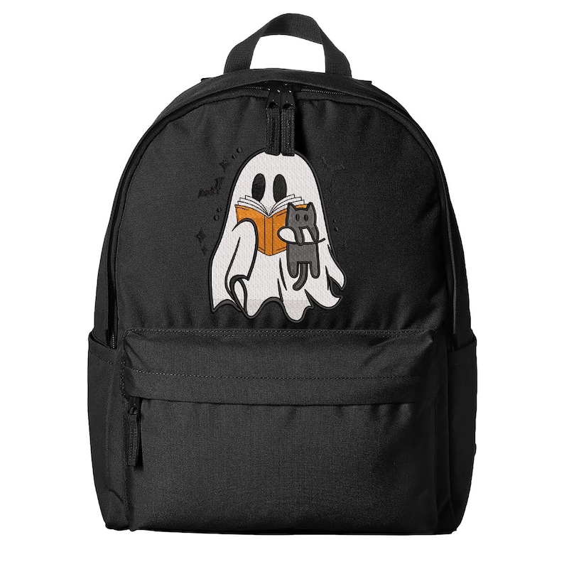 Puede incluir: Una mochila negra con un gr&aacute;fico bordado de un fantasma blanco que sostiene un libro naranja y un peque&ntilde;o gato gris. El dise&ntilde;o del fantasma incluye peque&ntilde;os detalles de estrellas negras. La mochila tiene un compartimento principal y un bolsillo frontal con cremallera.