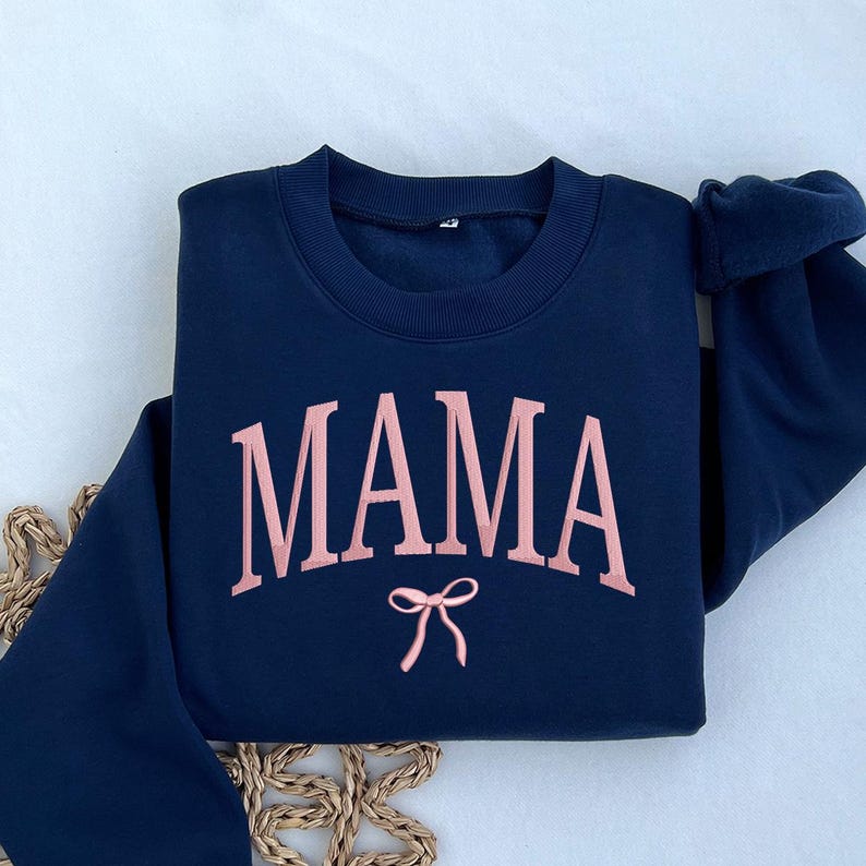 May include: A navy blue sweatshirt with the word "MAMA" in pink lettering and a pink bow underneath.