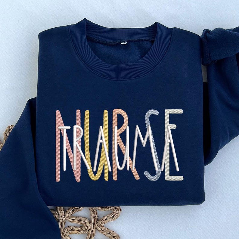 May include: A navy blue sweatshirt with the words "NURSE" and "TRAUMA" embroidered in colorful thread.