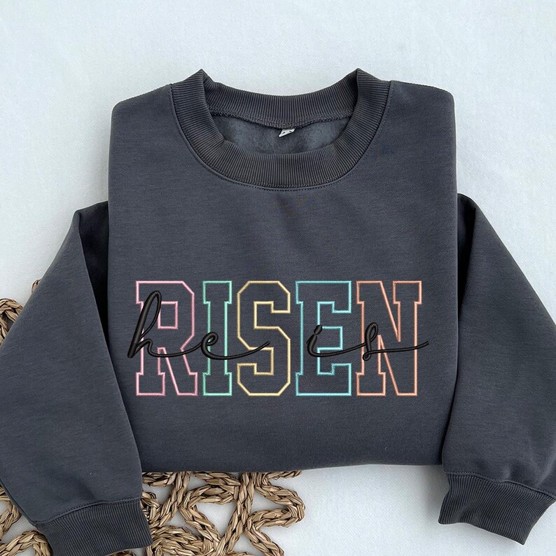 May include: A charcoal gray sweatshirt with the words "He is Risen" in rainbow colored letters.