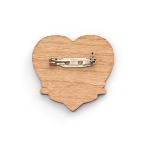 May include: A wooden heart-shaped pin with a metal clasp on the back.