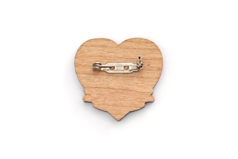 May include: A wooden heart-shaped pin with a metal clasp on the back.