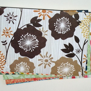 May include: A stack of patterned paper featuring brown, white, and gold floral designs. The paper is perfect for scrapbooking, card making, and other craft projects.