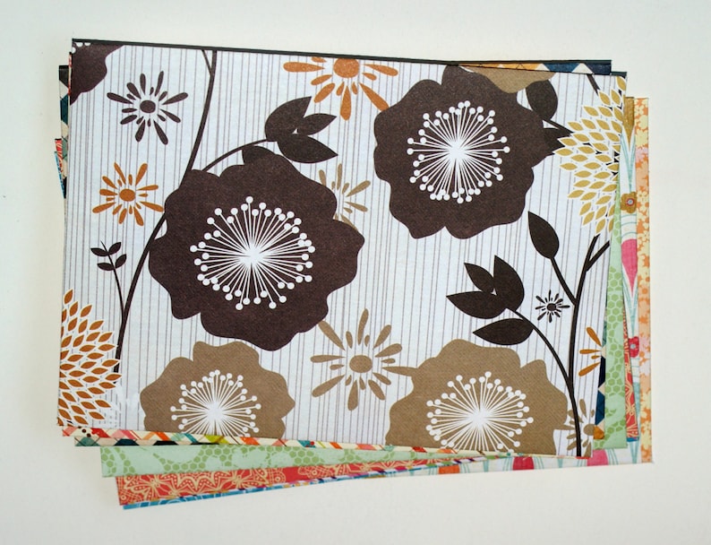 May include: A stack of patterned paper featuring brown, white, and gold floral designs. The paper is perfect for scrapbooking, card making, and other craft projects.