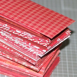 Peut inclure: Une pile d'enveloppes &agrave; motifs rouges et blancs. L'enveloppe du dessus a un motif &agrave; carreaux rouges et blancs.