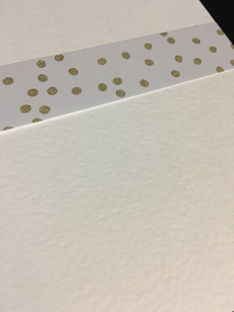 May include: A white card with a gold polka dot patterned strip across the top.