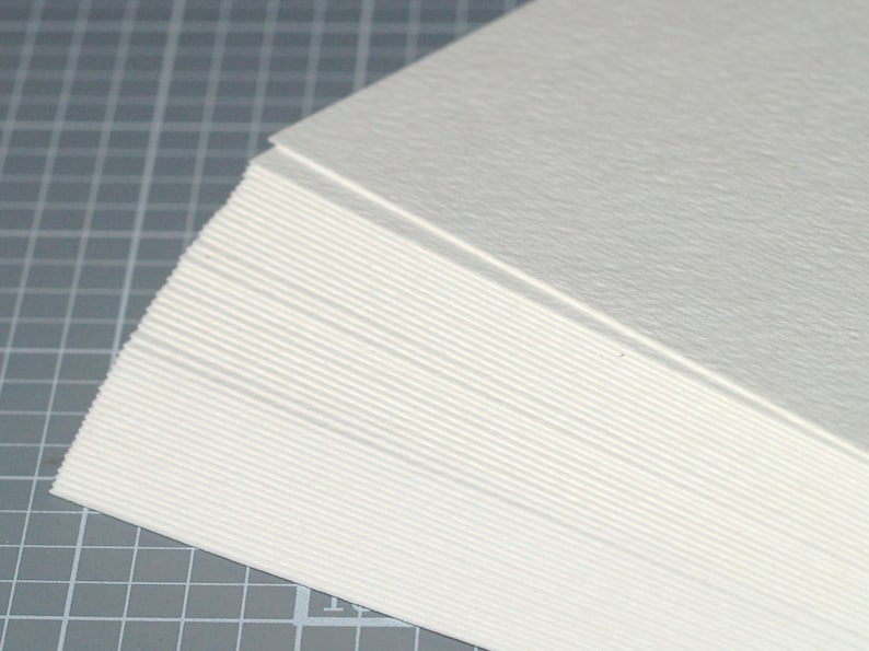Peut inclure: Une pile de feuilles de papier textur&eacute; blanc. Le papier est lisse et a une texture subtile.