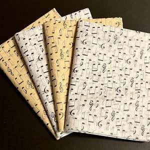 May include: Four sheets of tissue paper with a black musical note pattern. The sheets are in different shades of beige and white.
