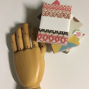 Peut inclure: Un ensemble de quatre petits carnets faits &agrave; la main avec des couvertures aux motifs color&eacute;s. Les couvertures pr&eacute;sentent une vari&eacute;t&eacute; de motifs, notamment des motifs floraux, g&eacute;om&eacute;triques et de dentelle. Les carnets sont reli&eacute;s avec une reliure blanche et ont une &eacute;tiquette blanche vierge sur la couverture avant.