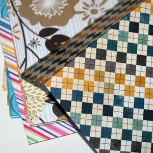 May include: A stack of patterned paper with a checkered design on top. The paper has a variety of colors, including blue, green, yellow, and brown.