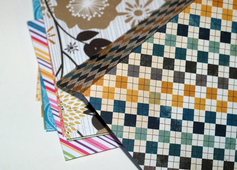 May include: A stack of patterned paper with a checkered design on top. The paper has a variety of colors, including blue, green, yellow, and brown.