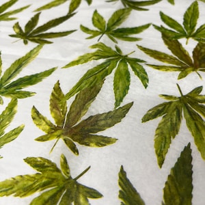 May include: White paper with a repeating pattern of green watercolour cannabis leaves.