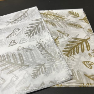 May include: Two sheets of white tissue paper with a gold and silver leaf pattern. The pattern features stylized leaves and hearts.