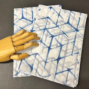 May include: A stack of white tissue paper with a blue geometric pattern. The pattern is made up of lines and squares.
