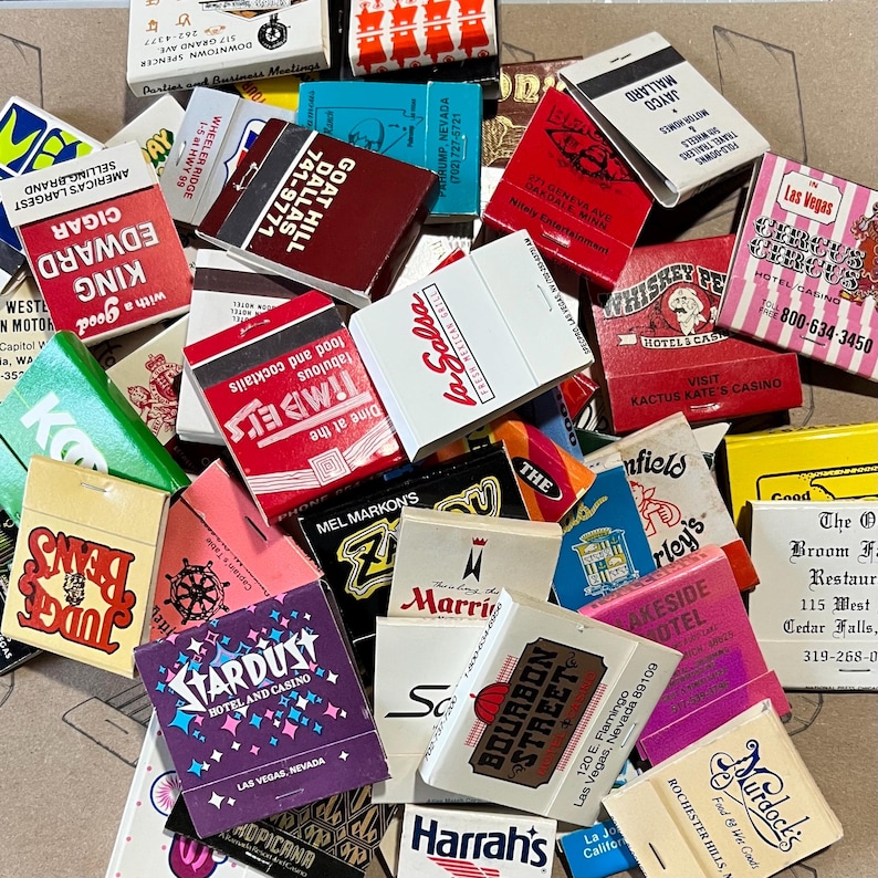 May include: A collection of vintage matchbook covers featuring various businesses and locations. The matchbooks are colorful and feature a variety of designs, including illustrations, text, and logos. Some of the matchbooks are from hotels, restaurants, and casinos. The matchbooks are a great example of vintage advertising and memorabilia.