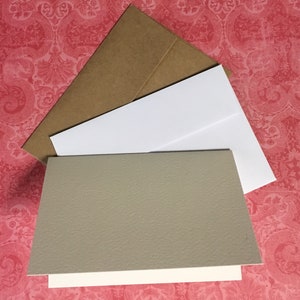 May include: A set of blank greeting cards with brown envelopes. The cards are white with a textured grey cardstock insert.