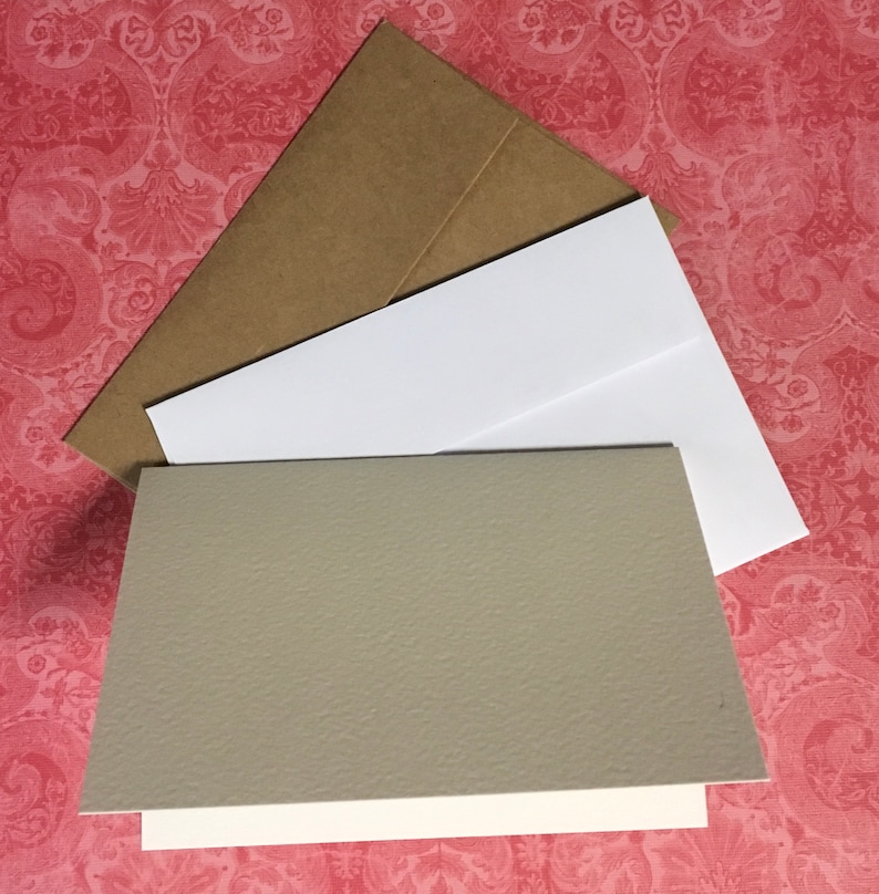 May include: A set of blank greeting cards with brown envelopes. The cards are white with a textured grey cardstock insert.