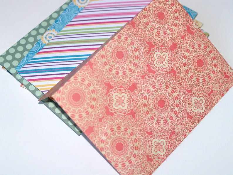 May include: A stack of patterned paper with a red and cream design on top. The paper has a delicate lace pattern.