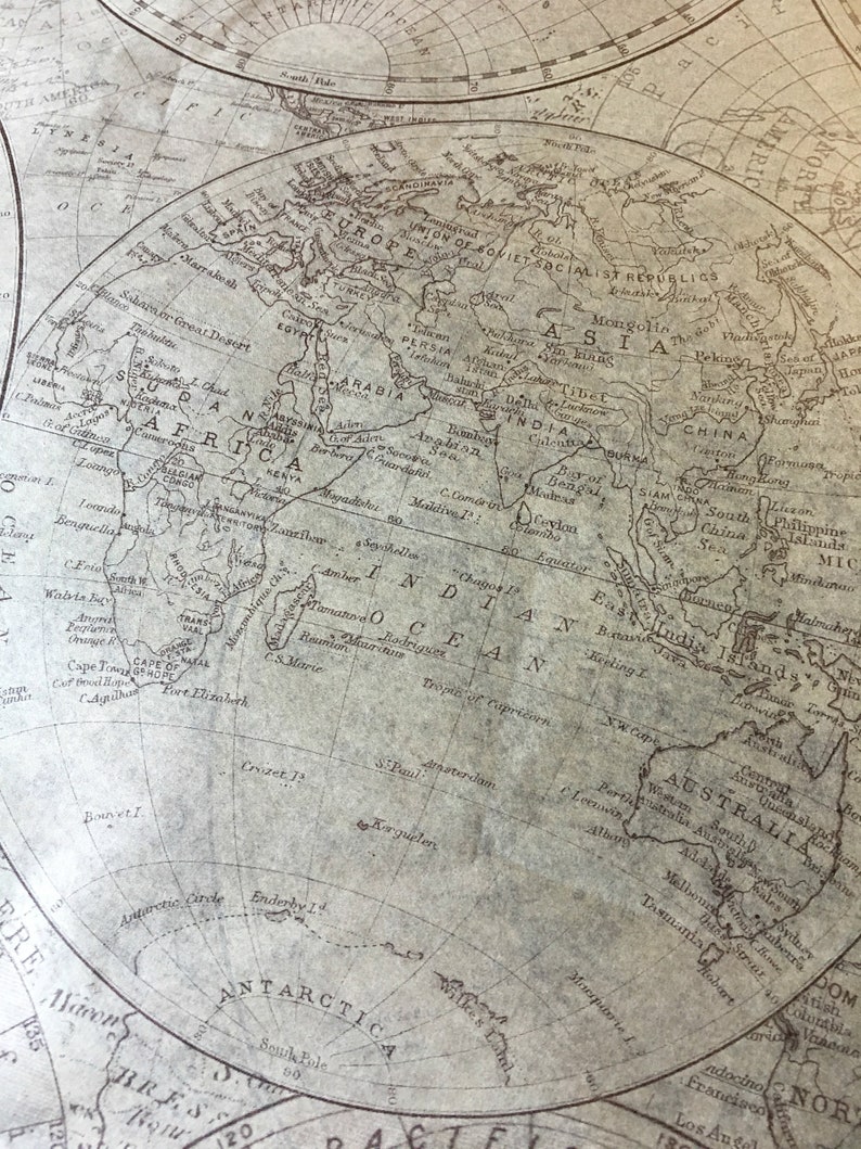 Pu&ograve; includere: Una mappa del mondo vintage stampata su carta con uno schema di colori marrone e beige. La mappa mostra i continenti del mondo con i nomi dei paesi e le principali citt&agrave; etichettate. La mappa &egrave; centrata sull'Oceano Indiano e include i continenti di Africa, Asia, Australia e Antartide.