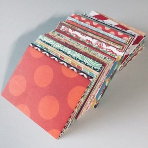 Peut inclure: Une pile d'enveloppes en papier &agrave; motifs color&eacute;s, avec une enveloppe rouge &agrave; pois blancs sur le dessus.