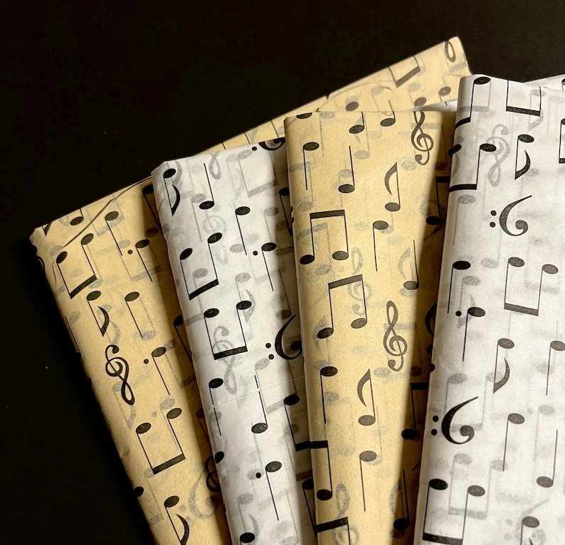 May include: Four sheets of wrapping paper with a black and white musical note pattern. The paper is beige, white, and cream.