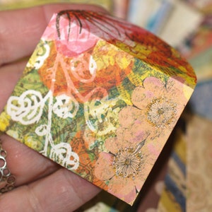 May include: A small, folded box with a colourful floral pattern. The box is made of paper and has a textured surface. The flowers are pink, orange, and yellow.