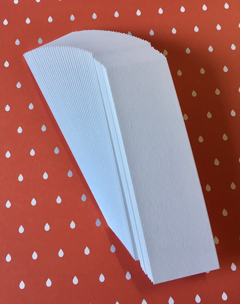 K&ouml;nnte beinhalten: Ein Stapel wei&szlig;er Papiert&uuml;ten mit einem strukturierten, gerippten Design. Die T&uuml;ten sind angewinkelt, wodurch ihre gefalteten Kanten sichtbar werden. Der Hintergrund ist rot-orange mit einem Muster aus wei&szlig;en Tropfen.