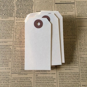 May include: Three blank white gift tags with brown paper circles and a hole for string. The tags are stacked on top of each other. The text on the tags reads "CAR TOPOGRAPHICAL DRAWING" and "Stepping onto the trail and recording each step and length, is how we record everything. Keeping it all on paper becomes very cumbersome, for some, but very comber full for others."