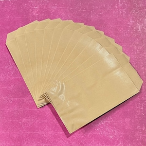 May include: A fan-shaped arrangement of multiple rectangular light brown paper envelopes. Each envelope features a smooth, matte texture and a standard flap closure at the top, layered neatly to display the uniform tan color and paper construction.