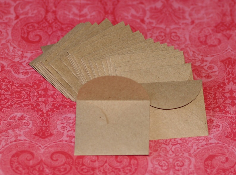 May include: A stack of brown paper envelopes with rounded corners. The envelopes are arranged in a fan shape and are ready to be used for sending letters or small gifts.