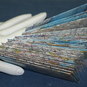 May include: A stack of folded maps with a blue and white color scheme. The maps are folded in a fan shape and show various geographical features.