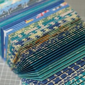 May include: A stack of folded paper with a blue and white patterned design. The paper is folded in a way that creates a fan-like shape.