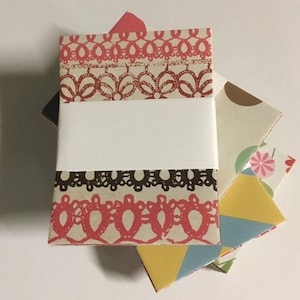 Peut inclure: Un ensemble de quatre petits carnets en papier d&eacute;coratifs avec des motifs diff&eacute;rents. Le carnet du haut a un motif de dentelle rose et blanc, le deuxi&egrave;me carnet a un motif de dentelle marron et blanc, le troisi&egrave;me carnet a un motif g&eacute;om&eacute;trique marron et blanc, et le carnet du bas a un motif g&eacute;om&eacute;trique jaune, bleu et blanc.