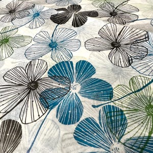 May include: A fabric with a repeating floral pattern. The flowers are in shades of black, teal, and green, with white and gray accents. The flowers have a linear design, with thin lines radiating from the center.