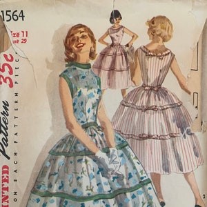 May include: Vintage Simplicity sewing pattern for a dress, pattern number 1564, size 11, bust 29. The pattern shows three women wearing different versions of the dress. One dress is floral print, one is striped, and one is solid.