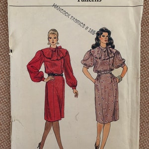 May include: Vogue Patterns sewing pattern number 8487 for sizes 12-14-16. The pattern features two women wearing dresses with ruffled collars and long sleeves. The dress on the left is red and the dress on the right is a floral print.