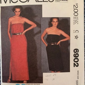 May include: A McCall's sewing pattern for a sleeveless dress with a strapless neckline. The pattern is for a size small and has a 90 minute average sewing time. The pattern is for stretch knits only. The pattern number is 6902.
