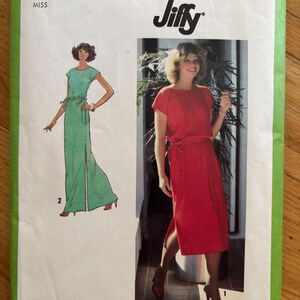 Peut inclure: Une pochette de patron de couture Simplicity 8981 Jiffy pour une robe en taille medium 14-16. Le devant présente une illustration verte d'une robe longue et une photo d'une personne portant une version rouge de la même robe à manches courtes.