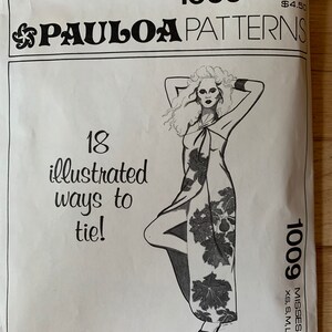 May include: A vintage Paula Patterns sewing pattern, featuring a drawing of a woman in a leaf-patterned wrap dress. The pattern includes 18 illustrated ways to tie the dress. The pattern is size XS, S, M, L, XL.