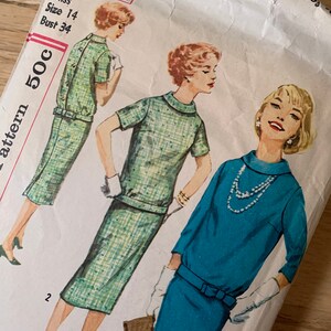 May include: Vintage sewing pattern for a dress, featuring three women wearing different styles. The pattern number is 2600 and the size is 14. The dress on the left is green and white plaid, the dress in the center is green and white plaid, and the dress on the right is blue.