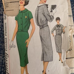 May include: Vintage sewing pattern for a dress with a skirt and a top. The pattern shows three different styles of the dress. One style is a green dress with a white collar and a star pin. Another style is a black and white gingham dress with a white collar. The third style is a black and white gingham dress with a white collar and a bow.