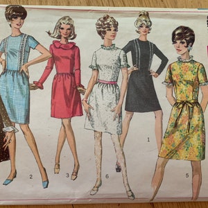 May include: Vintage Simplicity sewing pattern envelope featuring illustrations of six different dresses. The dresses are in various colors and styles, including a polka-dot dress, a plaid dress, and a floral print dress. The envelope indicates size 14, bust 36.