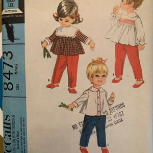 May include: Vintage McCall's sewing pattern for toddler's clothing. The pattern includes three tops with smocking and pants. The pattern is for size 6 months and includes a transfer for smocking. The pattern is printed on blue paper with the text "McCall's Blue" and "Stamps once on most light or dark materials. Will not show on similar color or like blue."