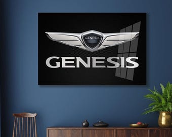 May include: A framed wall art piece featuring the Genesis logo. The logo is a silver emblem with a wing-like design and the word "GENESIS" in silver lettering against a black background. The artwork is displayed on a dark blue wall.