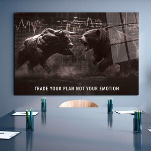 May include: A monochrome print depicting a bull and a bear in a confrontational pose, set against a stock market backdrop. The text "TRADE YOUR PLAN NOT YOUR EMOTION" is displayed. The artwork is mounted on a wall above a conference table.