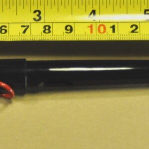 K&ouml;nnte beinhalten: Ein schwarzer Stift mit rotem Clip und Spitze, etwa 15 cm lang, liegt neben einem gelben Ma&szlig;band. Das Band zeigt Messungen in Fu&szlig; und Zoll an. Der Stift hat ein schlankes, modernes Design.